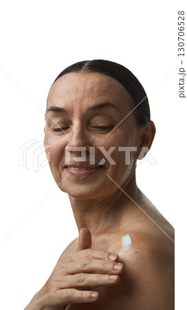 Mature woman applying cream on shoulder with calm smile 130706528