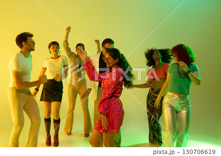Group of stylish friends dancing together in neon yellow atmosphere Group of stylish friends dancing together in neon yellow atmosphere 130706619