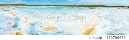 Salt lake with white mineral crystals and turquoise water against hills and sky Salt lake with white mineral crystals and turquoise water against hills and sky 130706653