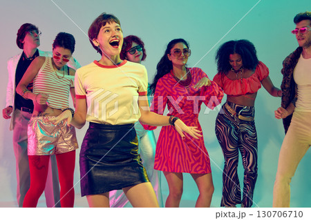Smiling woman enjoying dance surrounded by colorful retro friends 130706710