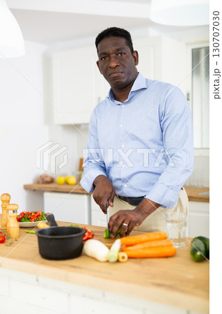 Man making dinner at kitchen table 130707030