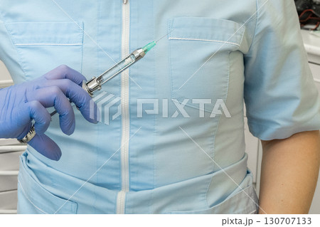 Doctor in medical gown and gloves holds syringe in her hand for injections and vaccinations. Health care in hospital 130707133
