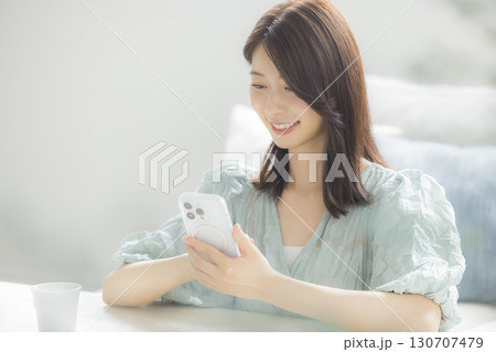 部屋でスマホを見る女性 130707479
