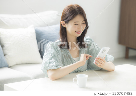 部屋でスマホを見る女性 130707482