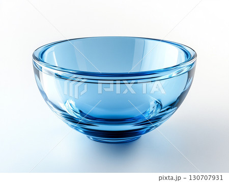 A close-up of a clear, light blue glass bowl on a white surface, showcasing its smooth, translucent surface and a subtle spiral pattern at its base. 130707931