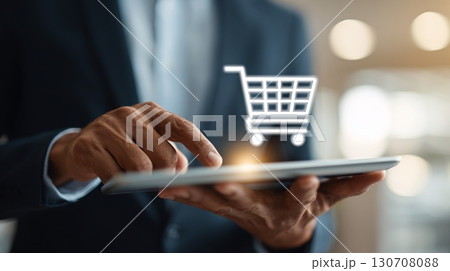 Online Shopping: A man in a suit uses a tablet for e-commerce, symbolized by a shopping cart icon. Easy purchasing from anywhere. Modern convenience. 130708088