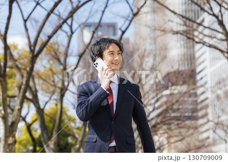 スマホで会話するビジネスマン 130709009