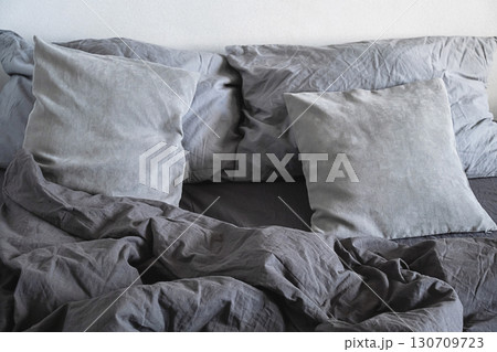 Grey pillows and crumpled linen bedding on bed. Grey pillows and crumpled linen bedding on bed. 130709723