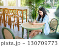 a portrait of beautiful happy asian woman traveler wearing a beautiful blue dress lifestyle enjoying holding using smartphone cellphone casual working in sitting coffee shop restaurant background 130709773