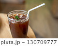 Close-up of Iced Black americano in a glass cup mug on  wood desk office desk in coffee shop at the cafe in garden,during business work concept 130709777