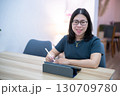 Portrait asian freelance people business female wearing glasses stylish hipster Draw or taking note on digital tablet with electronic pen for browsing internet, chatting and blogging in coffee shop. 130709780