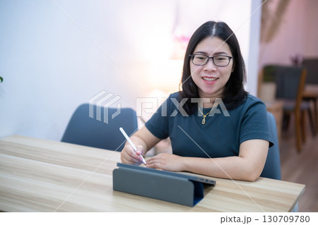 Portrait asian freelance people business female wearing glasses stylish hipster Draw or taking note on digital tablet with electronic pen for browsing internet, chatting and blogging in coffee shop. 130709780
