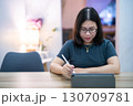 Portrait asian freelance people business female wearing glasses stylish hipster Draw or taking note on digital tablet with electronic pen for browsing internet, chatting and blogging in coffee shop. 130709781