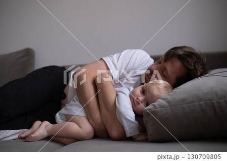 dad and little toddler girl sleeping together on sofa 130709805