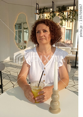 Woman enjoying orange juice in a modern, brightly lit interior cafe 130709867