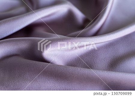 Luxurious purple fabric showcasing smooth and elegant folds in soft lighting 130709899