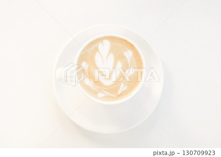 Latte coffee with artistic foam design served in a white cup and saucer 130709923