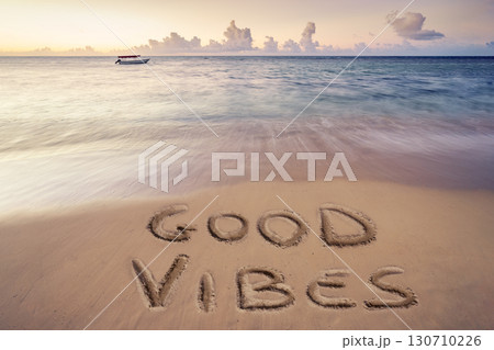handwritten good vibes on sandy beach 130710226