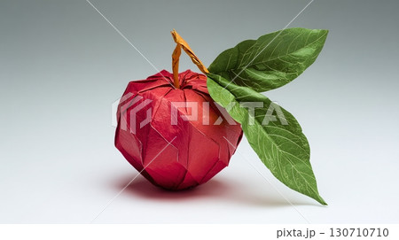 Origami apple with leaves. A beautiful representation of this art. Red paper folded to create a three-dimensional apple, showcasing intricate details. 130710710