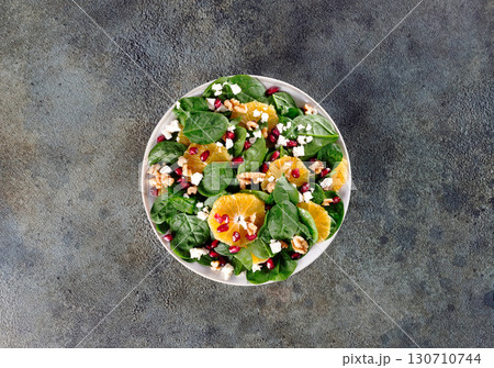 Green salad with oranges, pomegranate, walnuts and feta cheese. Vegetarian salad. Top view. 130710744