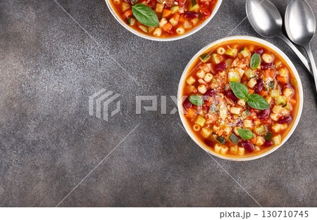 Vegetable soup with beans and pasta on gray background. Italian food. Minestrone soup. Top view. Copy space. Vegetable soup with beans and pasta on gray background. Italian food. Minestrone soup. Top view. Copy space. 130710745