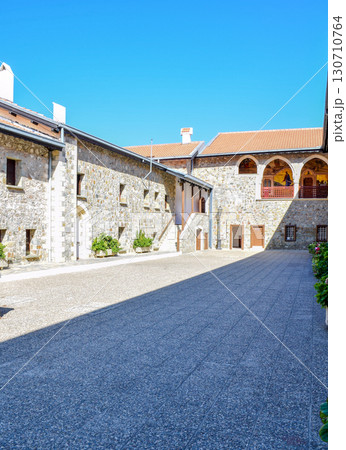 Historical stone monastery courtyard with arched frescoes in realistic style under bright clear sky. 130710764