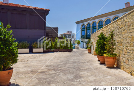 A quiet Mediterranean style courtyard with potted plants, a stone wall and colorful buildings A quiet Mediterranean style courtyard with potted plants, a stone wall and colorful buildings 130710766