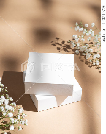 Two white square box on a beige background with gypsophila flowers and soft shadows. Two white square box on a beige background with gypsophila flowers and soft shadows. 130710776