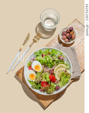 Tuna salad with cherry tomatoes, eggs, olives and cucumbers in a plate on a wooden board Tuna salad with cherry tomatoes, eggs, olives and cucumbers in a plate on a wooden board 130710795