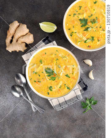 Traditional Indian Mulligatawny soup with lentils and chicken on a dark background. Top view. Traditional Indian Mulligatawny soup with lentils and chicken on a dark background. Top view. 130710819