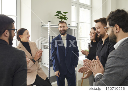 Smiling man and business leader with team of people applauding him at the office. Smiling man and business leader with team of people applauding him at the office. 130710926