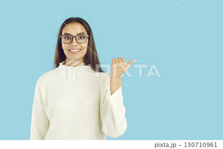 Happy young woman pointing to side with thumb finger Happy young woman pointing to side with thumb finger 130710961