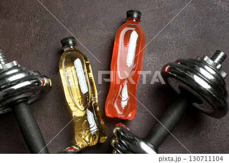 Isotonic sport drink with dumbbells on dark background 130711104