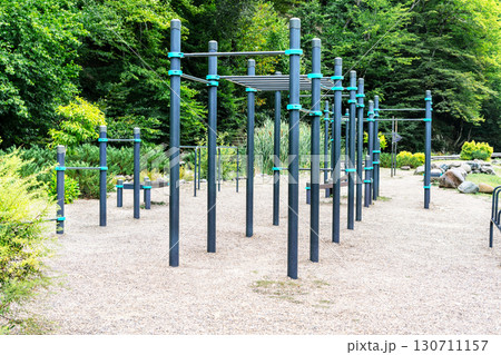 Street workout area with metal exercise structures located in a park. Sports equipment for bodyweight training, gymnastics, and healthy outdoor activity in an eco-friendly setting Street workout area with metal exercise structures located in a park. Sports equipment for bodyweight training, gymnastics, and healthy outdoor activity in an eco-friendly setting 130711157
