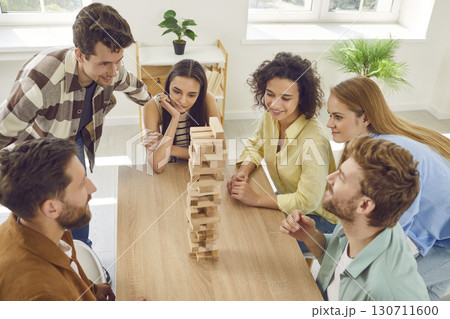 Group of a happy friends playing together with wooden building blocks at home. Group of a happy friends playing together with wooden building blocks at home. 130711600