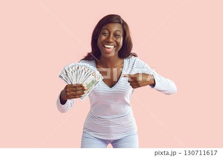 Happy young African American woman is smiling and holding a fan of her cash money Happy young African American woman is smiling and holding a fan of her cash money 130711617