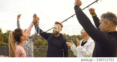Happy young people giving high five each other rejoicing the success in sport training outdoors. 130711751