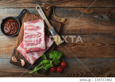 Raw pork ribs with spices, salt and rosemary on dark wooden background 130711962