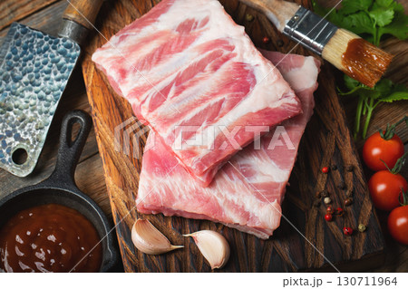Raw pork ribs with spices, salt and rosemary on dark wooden background Raw pork ribs with spices, salt and rosemary on dark wooden background 130711964