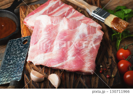 Raw pork ribs with spices, salt and rosemary on dark wooden background Raw pork ribs with spices, salt and rosemary on dark wooden background 130711966