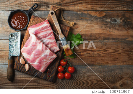 Raw pork ribs with spices, salt and rosemary on dark wooden background Raw pork ribs with spices, salt and rosemary on dark wooden background 130711967