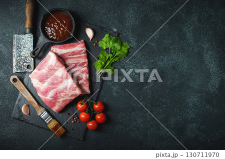 Raw meat. Raw pork ribs from the back with meat on a black background. background image Raw meat. Raw pork ribs from the back with meat on a black background. background image 130711970