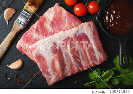 Raw meat. Raw pork ribs from the back with meat on a black background. background image 130711980