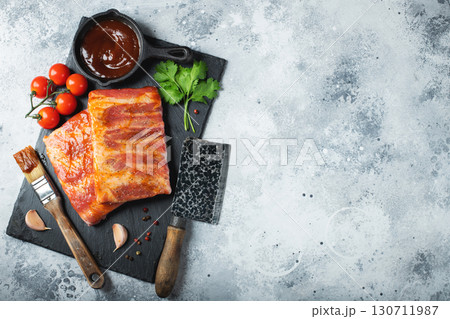 Ready for BBQ raw pork spare ribs with barbecue sauce. Black background. Top view 130711987