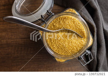 Uncooked couscous in jar on wooden table. Top view. 130712021