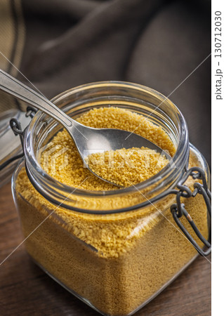 Uncooked couscous in jar on wooden table. 130712030