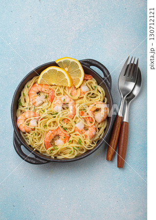 Delicious seafood pasta spaghetti with shrimps dish garnished with lemon and parsley top view on light blue background Delicious seafood pasta spaghetti with shrimps dish garnished with lemon and parsley top view on light blue background 130712121