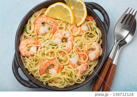 Delicious seafood pasta spaghetti with shrimps dish garnished with lemon and parsley top view on light blue background 130712128