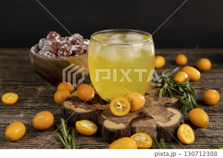 citrus orange juice and fresh kumquat fruits on a wooden table, delicious and fresh orange juice and fresh kumquat fruits next to a glass citrus orange juice and fresh kumquat fruits on a wooden table, delicious and fresh orange juice and fresh kumquat fruits next to a glass 130712308