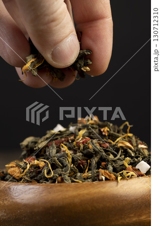 large-leaved green tea poured into a wooden cup with the addition of fruits , dry high-quality expensive tea in a wooden bowl 130712310